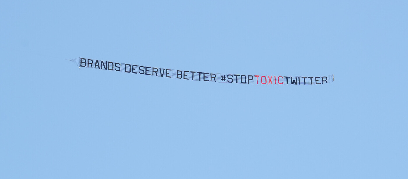 A banner flying over a Miami convention where Musk appeared reads "Brands deserve better. #StopToxicTwitter"